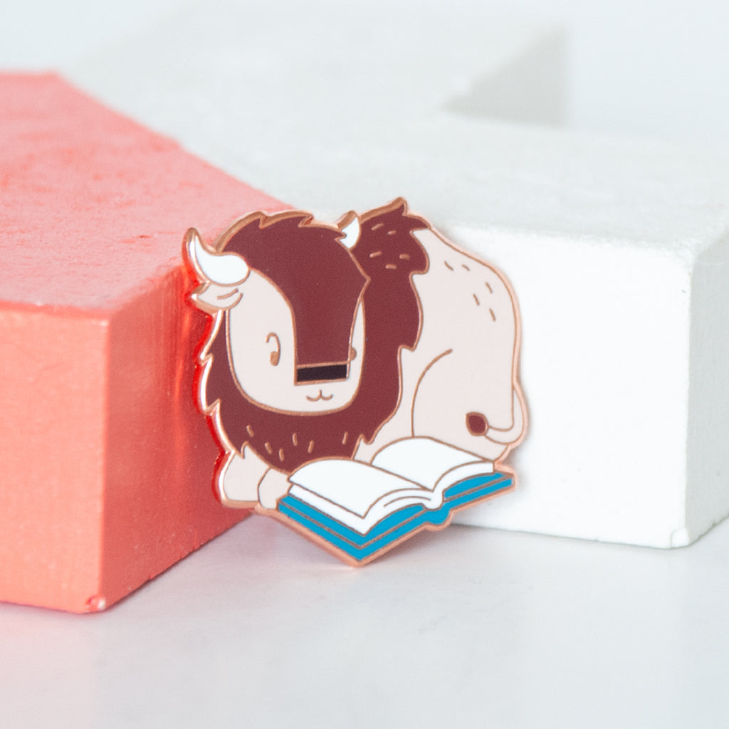 Wood buffalo or bison reading a book hard enamel pin