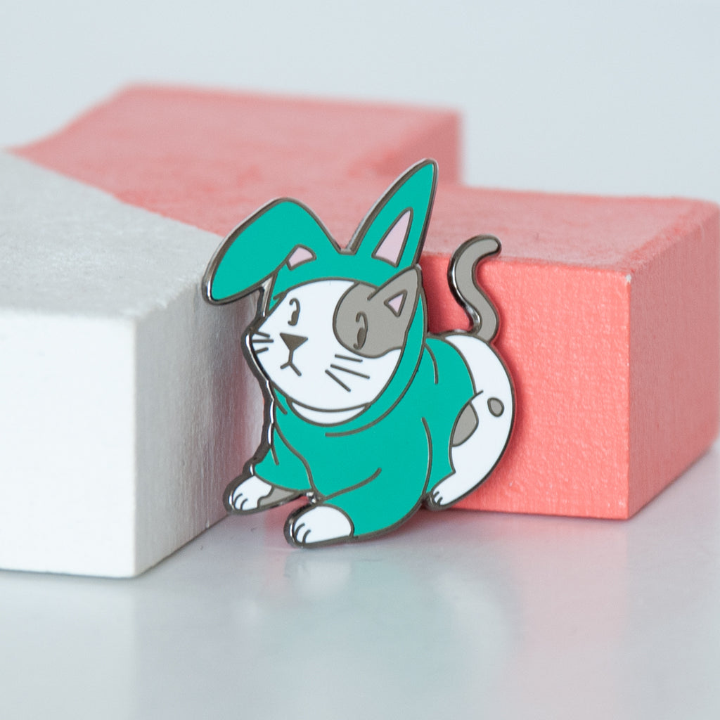 Cosplay white and grey kitty dressed in a turquoise bunny outfit hard enamel pin