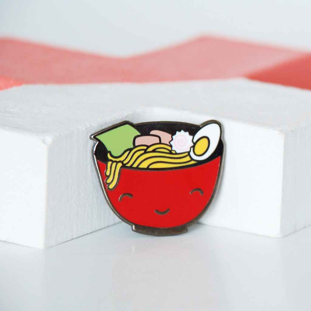 Red Bowl of steaming warm ramen noodles topped with seaweed, naruto, pork and egg enamel pin